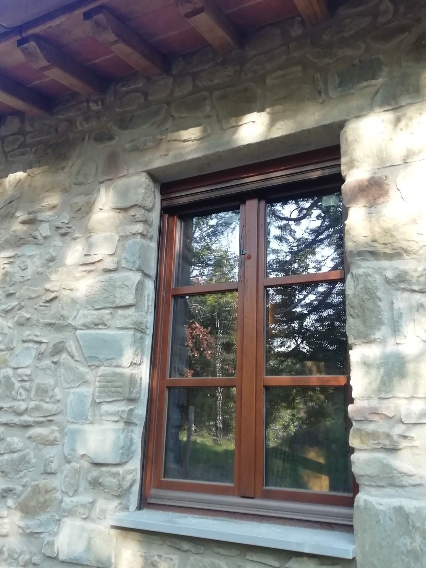 Finestra in legno con vetrocamera su facciata in pietra